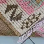 Folded corner of a turkish carpet with pink and brown diamond pattern
