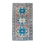 turkish carpet showing blue, pink, and cream tribal motifs with the woven backing.